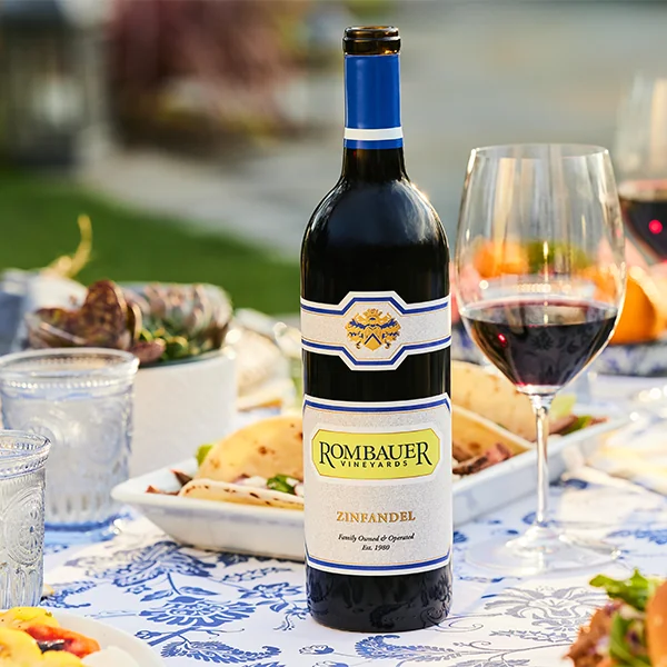 Zinfandel bottle and a glass on an outdoor dining table.