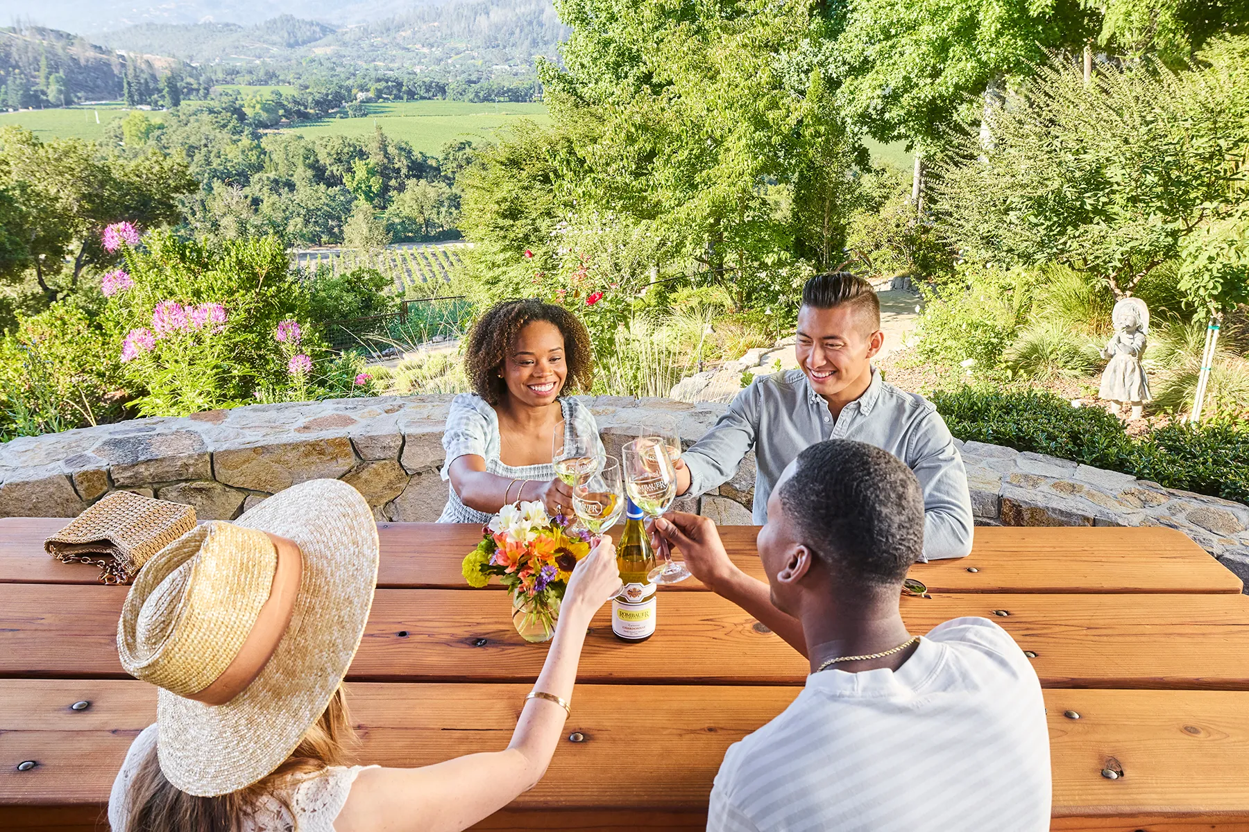 Guests toasting with glasses of Rombauer Chardonnay at a table overlooking the Napa Valley
